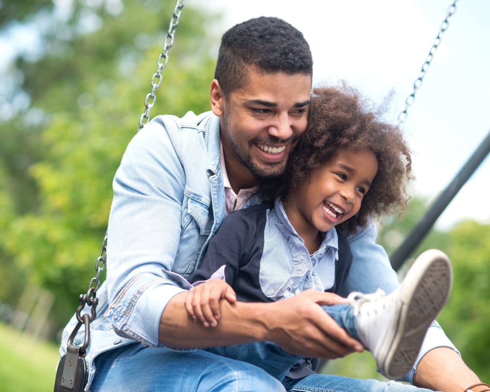 A father and daughter swinging on a swing at a playground at O'Neill Heights East in Oceanside, California