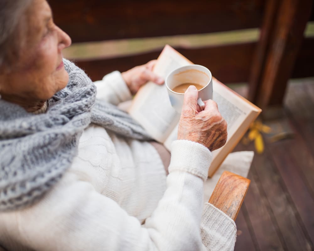 Resident drinking coffee and reading a book at The Pillars of Prospect Park in Minneapolis, Minnesota