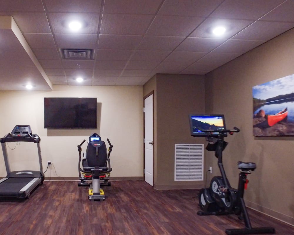 Resident gym with cardio equipment and large television at The Pillars of Mankato in Mankato, Minnesota