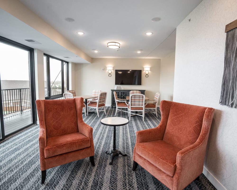 Resident recreation room with armchairs and large television at The Pillars of Lakeville in Lakeville, Minnesota