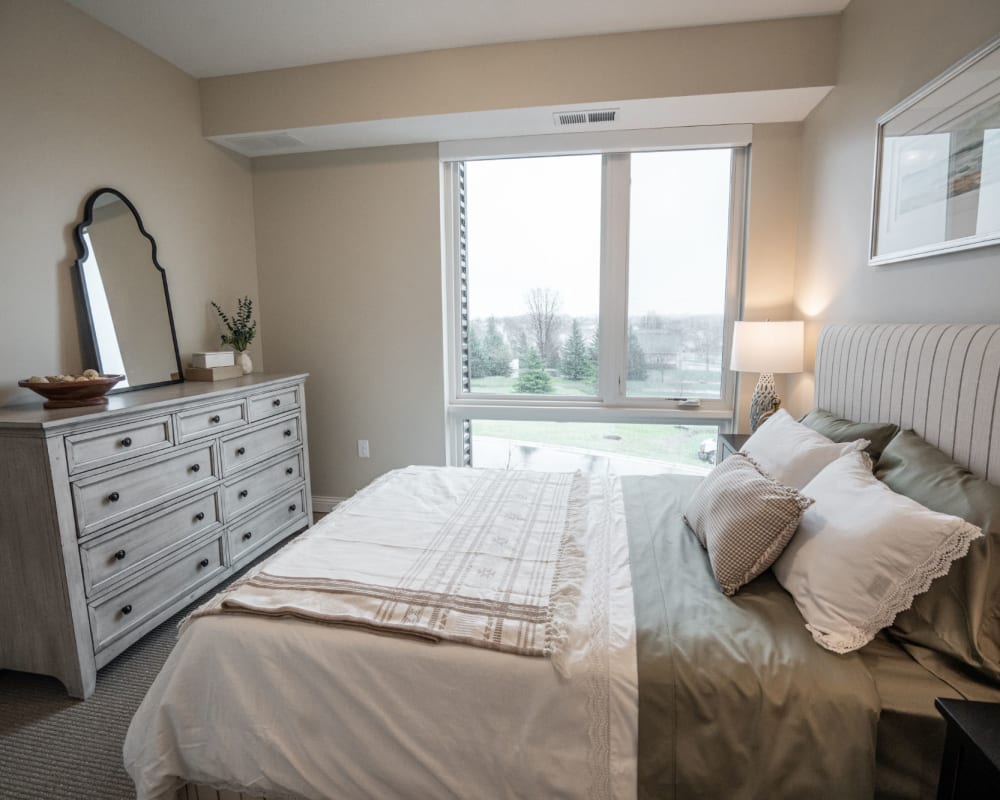 Resident bedroom with large well-lit window at The Pillars of Lakeville in Lakeville, Minnesota