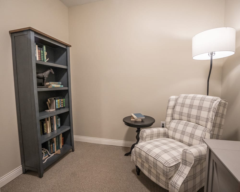 Reading corner with comfy armchair and bookshelf at The Pillars of Lakeville in Lakeville, Minnesota
