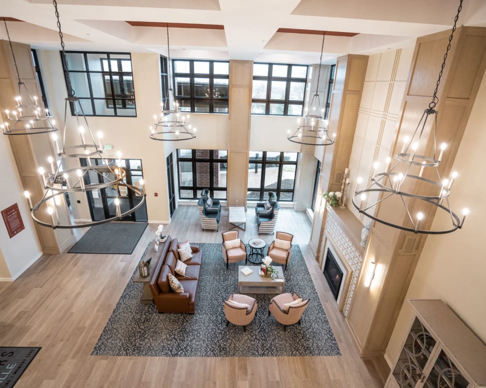 Main entrance and lobby with large area rug, comfy seating, and multiple chandeliers at The Pillars of Lakeville in Lakeville, Minnesota