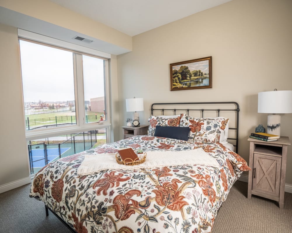 Resident bedroom with full size bed and large window at The Pillars of Lakeville in Lakeville, Minnesota