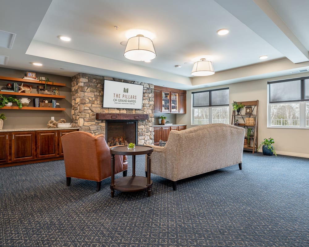 Resident lounge area with seating and stone fireplace at The Pillars of Grand Rapids in Grand Rapids, Minnesota