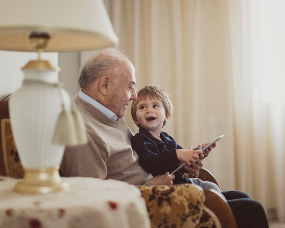 Resident and child playing with a tablet at The Pillars of Hermantown in Hermantown, Minnesota