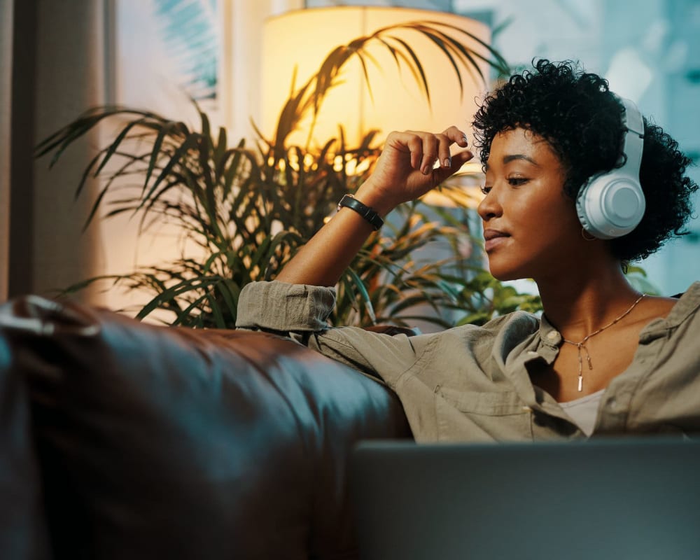 Resident sitting on her couch at home on her laptop at Amador Apartments in Hayward, California