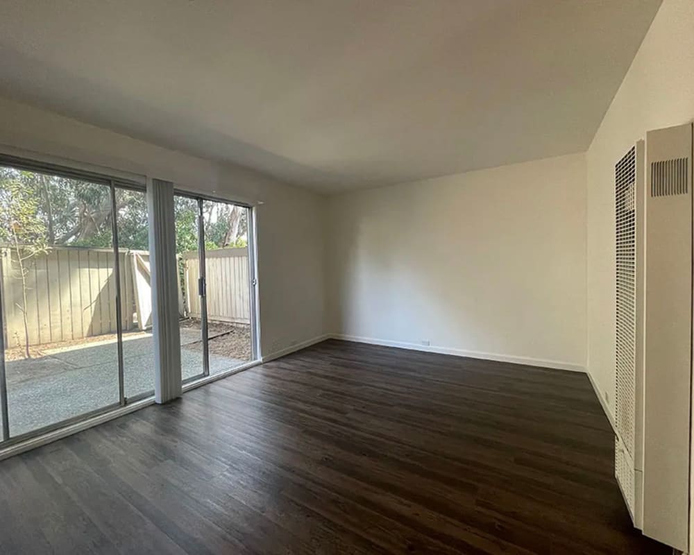 Living room with large windows and door to patio at 225 Clifton in Oakland, California
