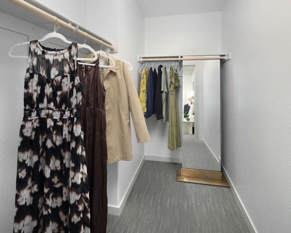 Walk-in closet with hanging clothes and dresses at SoCo Apartments in Napa, California