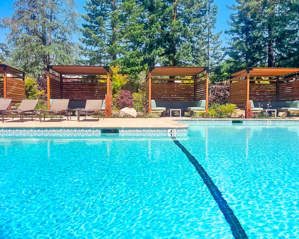 Sparkling swimming pool with Tuuci Cabanas at Brookdale Apartments in San Jose, California