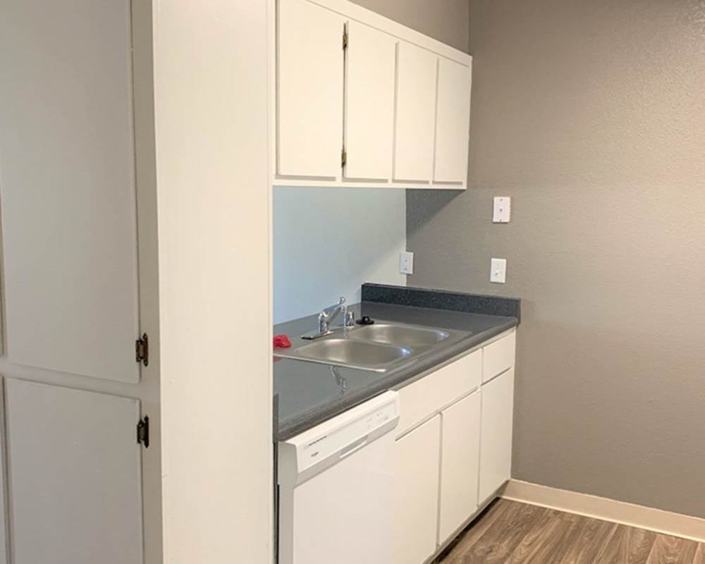 Kitchen island with dishwasher, sink with waterfall faucet, and granite countertops at Somerset Senior Apartments in Antioch, California