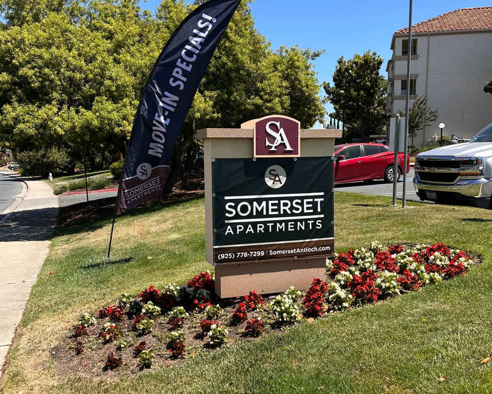 Front entrance sign of community grass and walking paths at Somerset Senior Apartments in Antioch, California