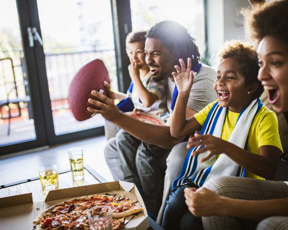 Residents watching soccer match and eating pizza in clubhouse at The Bayou District in Gulfport, Mississippi