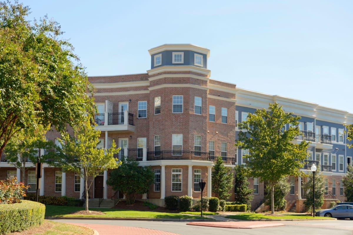 Beautiful brick building surrounded by trees and grass at Worthington Apartments & Townhomes in Charlotte, North Carolina