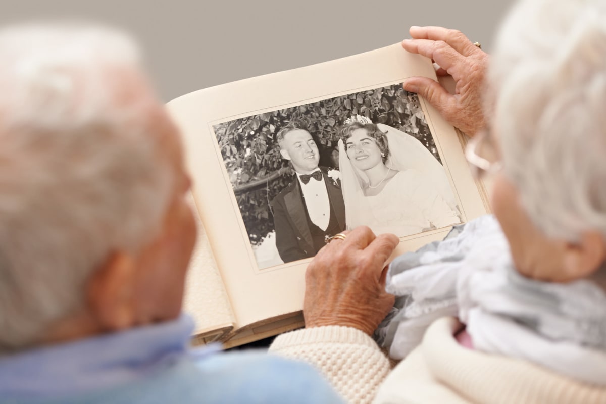 A resident couple looking through an old photo album at Oxford Glen Memory Care at Grand Prairie in Grand Prairie, Texas