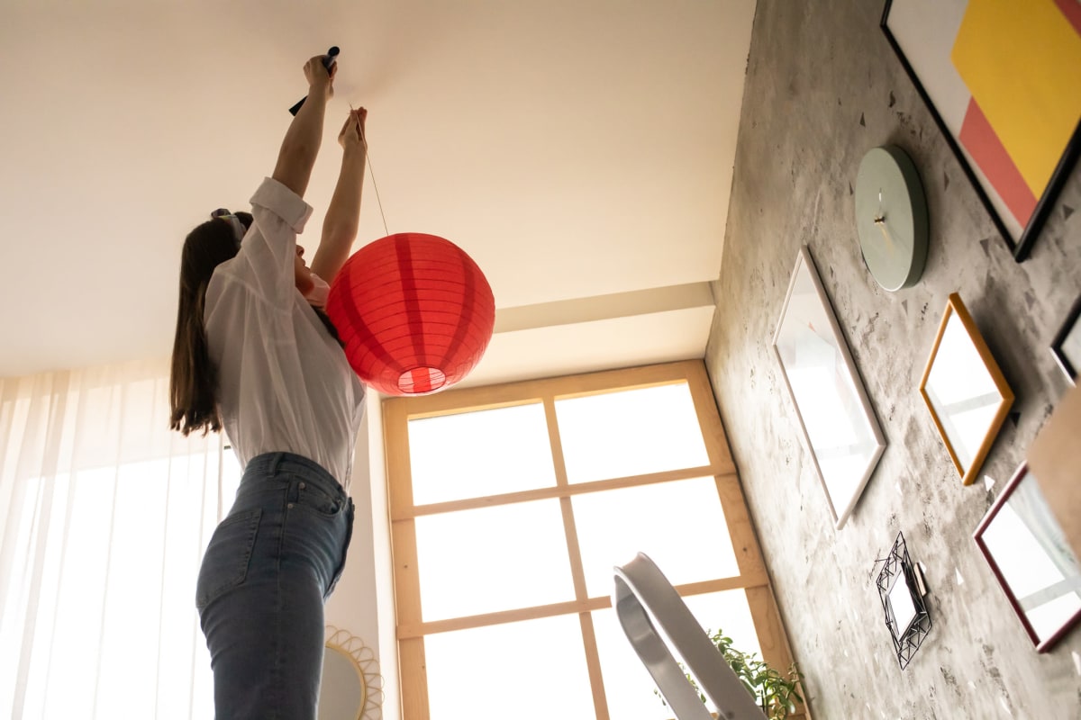 Resident hanging some decor from the high ceiling in her home at Solera at City Centre in Palm Beach Gardens, Florida