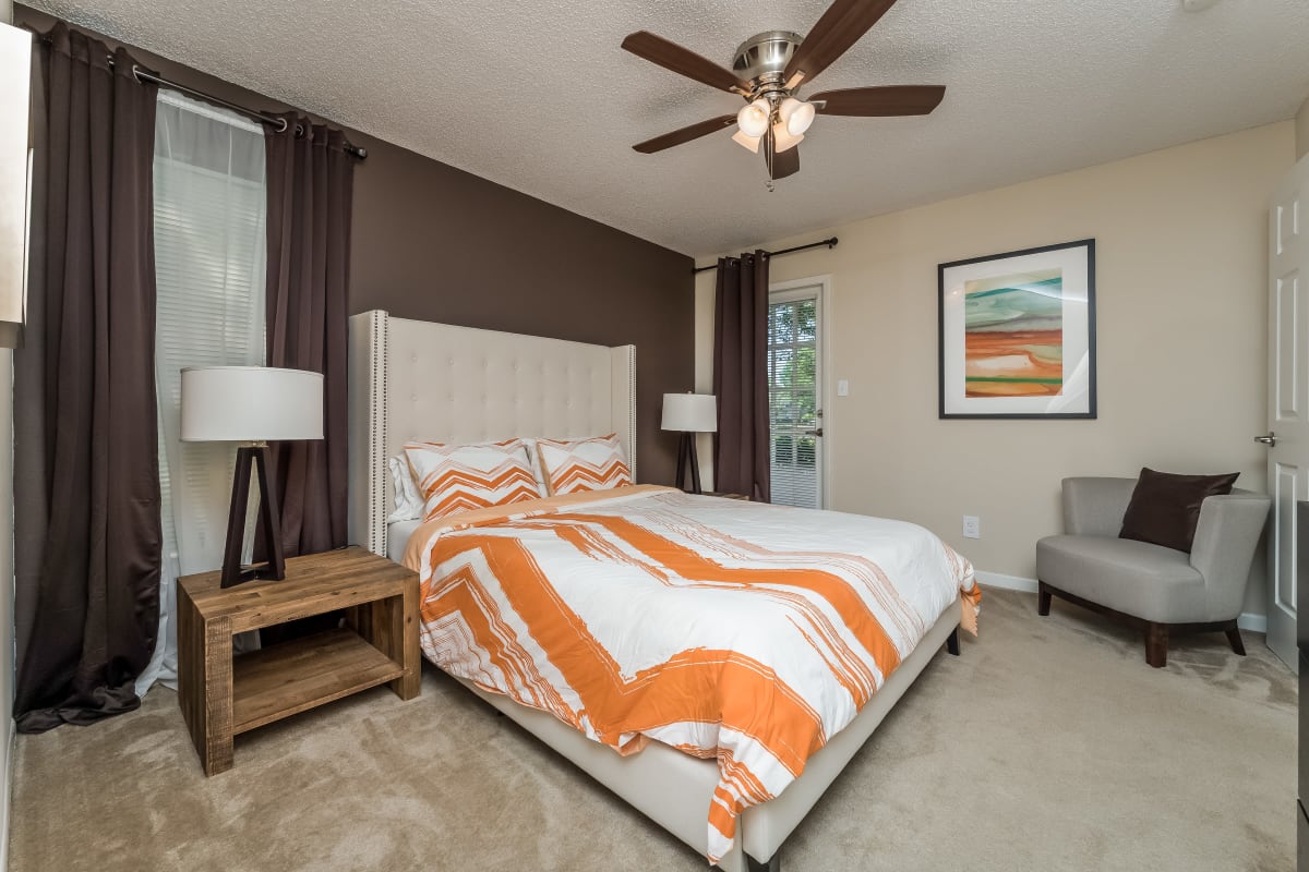 Model master bedroom with plush carpeting and a ceiling fan at Tuscany Pointe at Tampa Apartment Homes in Tampa, Florida