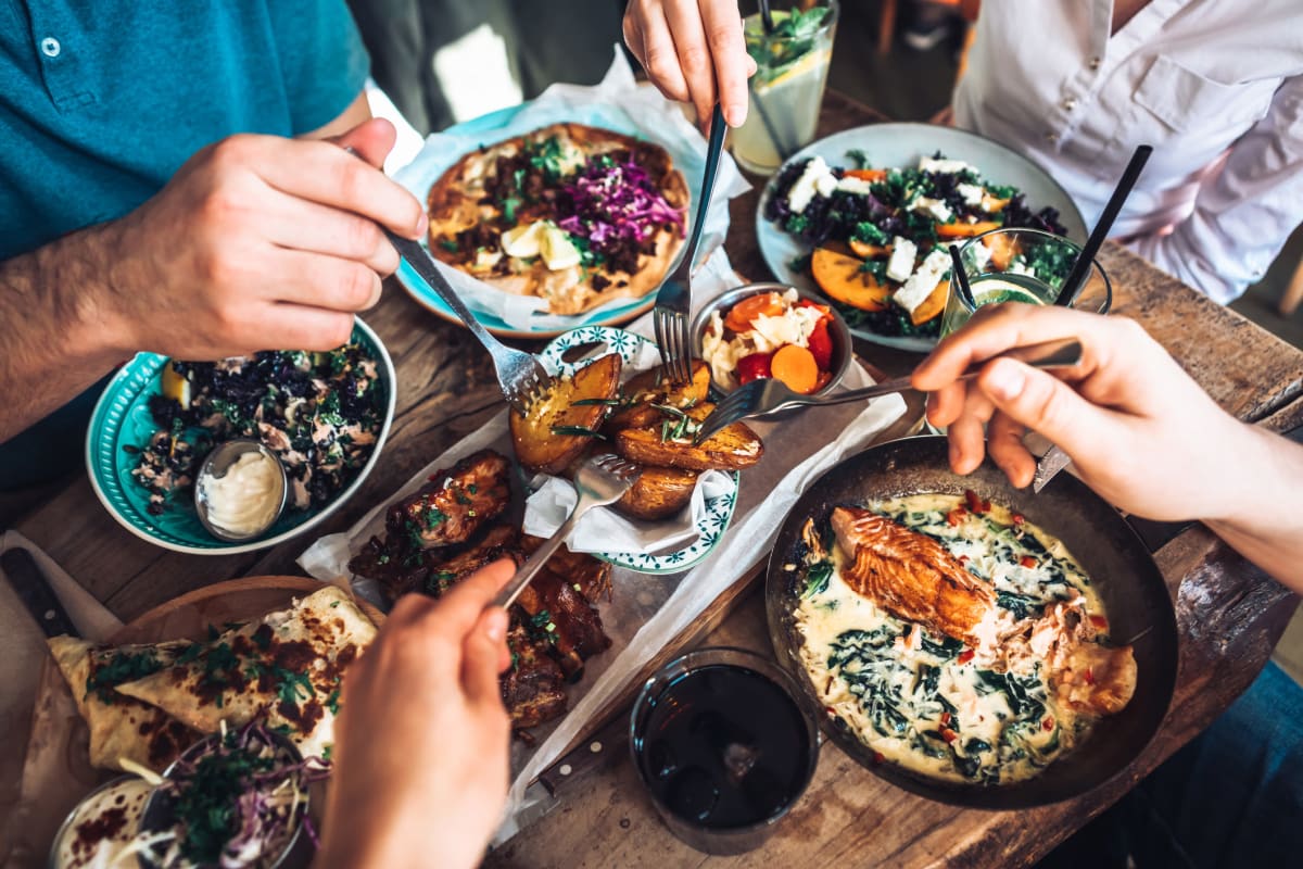 Resident friends diving into a delicious feast at their favorite restaurant near The Pointe at Siena Ridge in Davenport, Florida