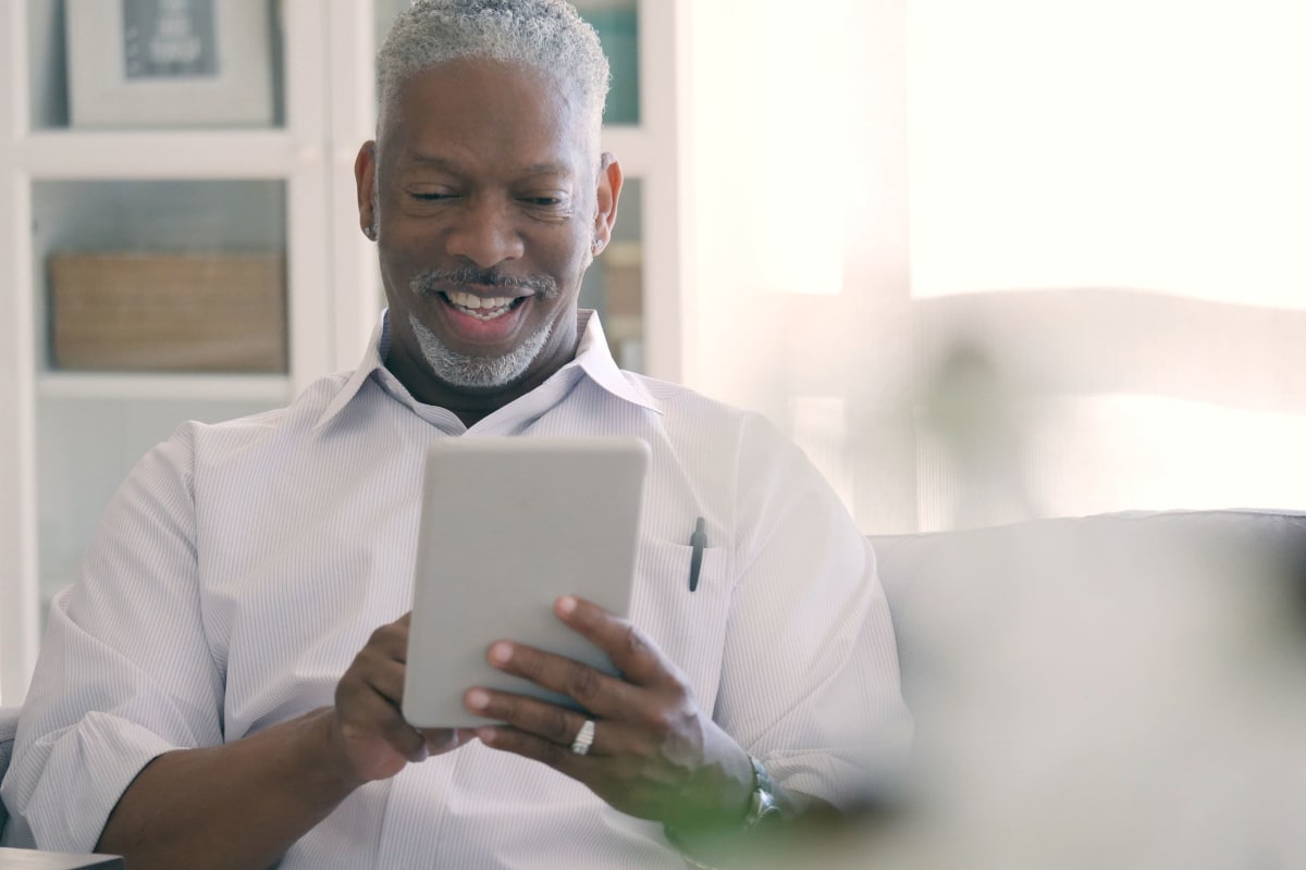 Happy resident checking the news on a tablet device in his new apartment at The Pointe at Siena Ridge in Davenport, Florida