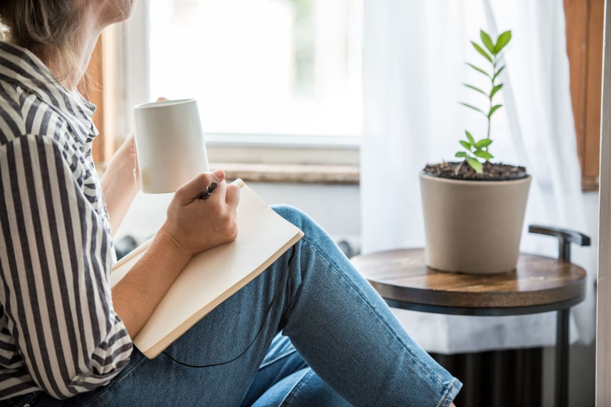 Resident journaling with a cup of tea in her apartment at The Pointe at Siena Ridge in Davenport, Florida