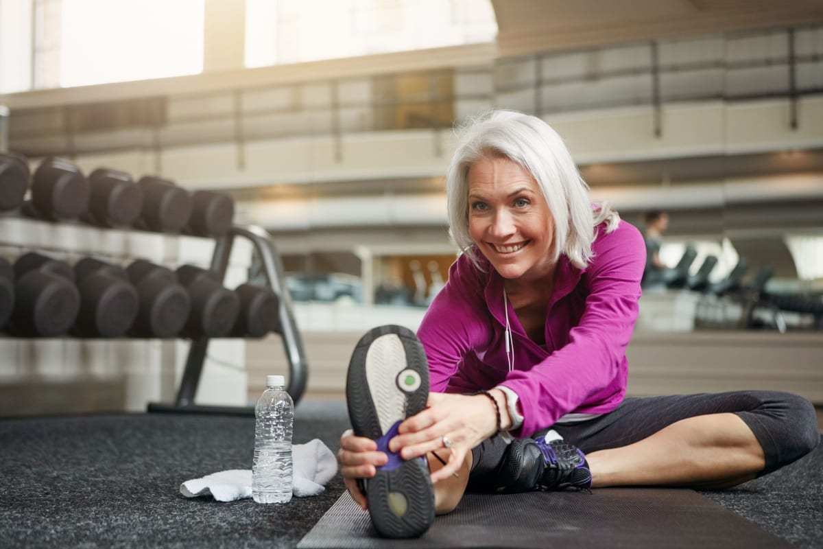 Resident stretching before her workout in the onsite fitness center at The Pointe at Siena Ridge in Davenport, Florida