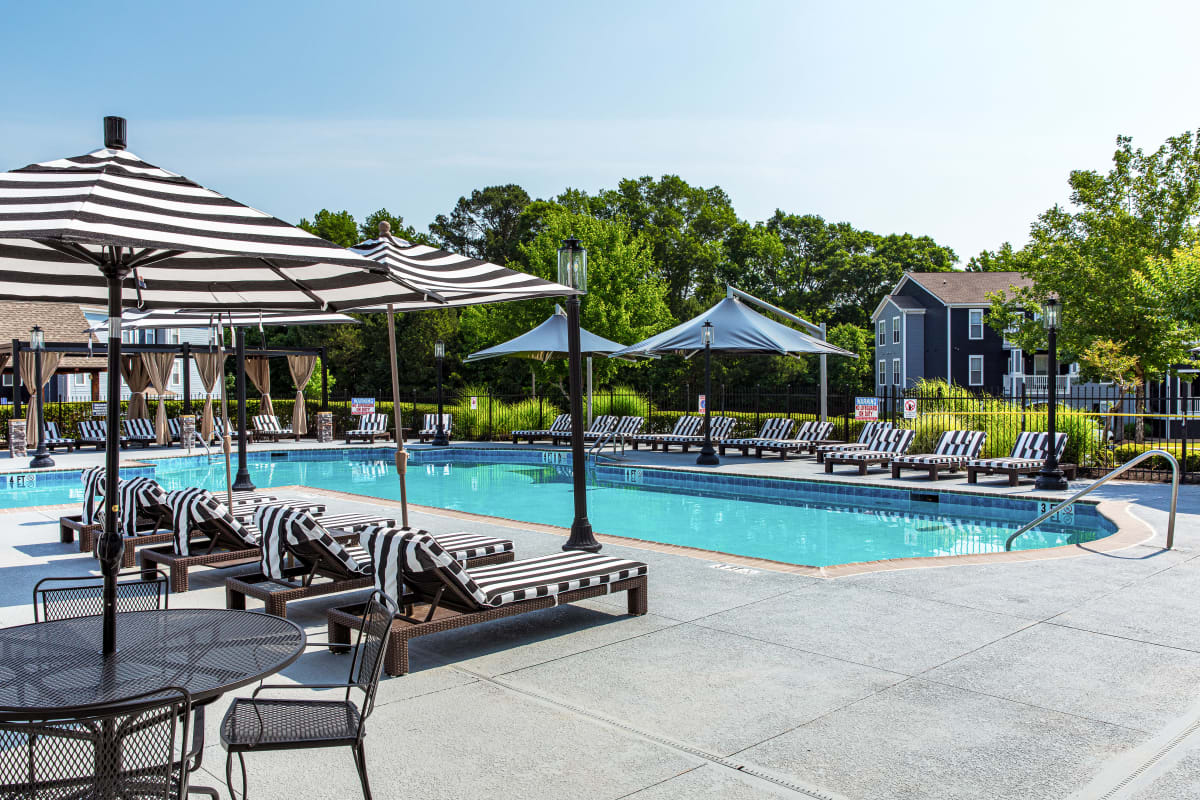 Patio table and luxury lounge chairs by the swimming pool at River Pointe in Carrollton, Georgia