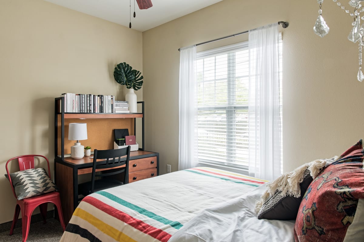 Model bedroom with a large window and desk at University Village in Greensboro, North Carolina