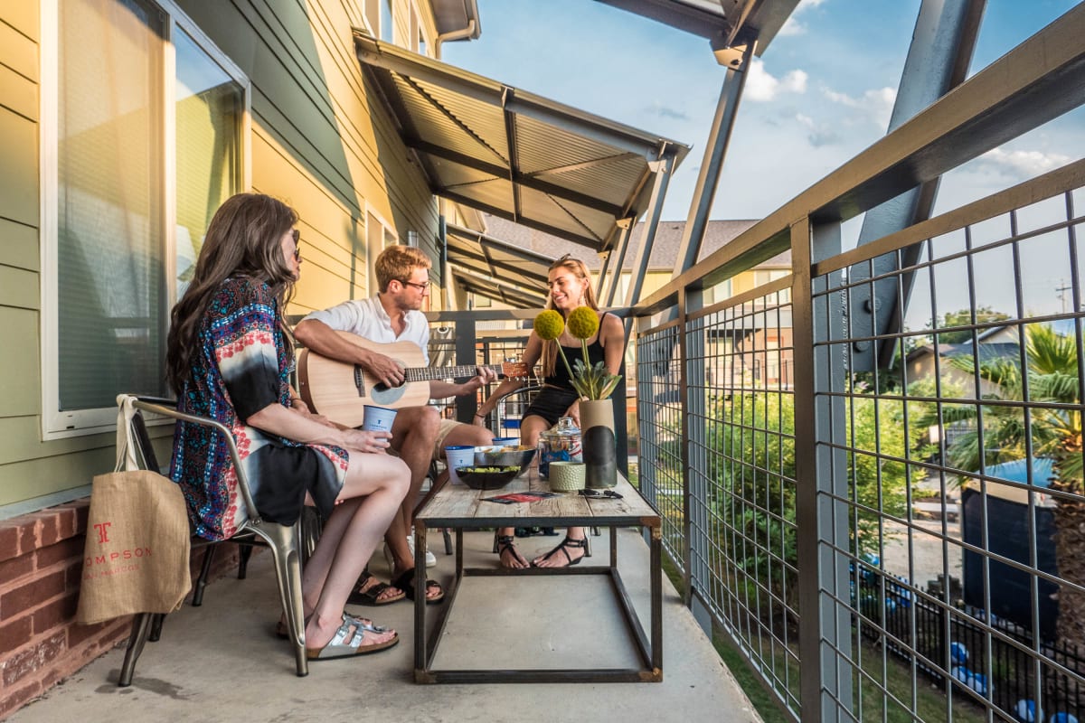 Residents hanging out and playing guitar on a private patio at The Thompson in San Marcos, Texas