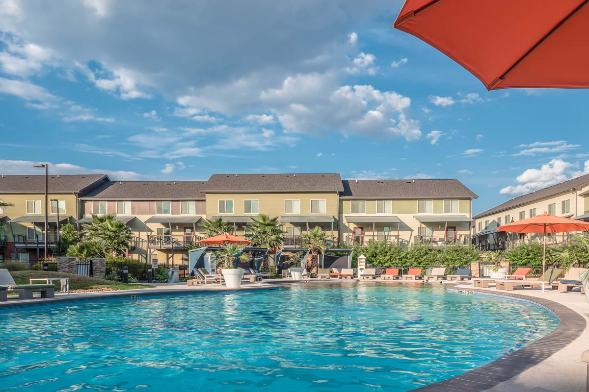 Sparkling beach-entry pool surrounded by lounge chairs and cabanas at The Thompson in San Marcos, Texas