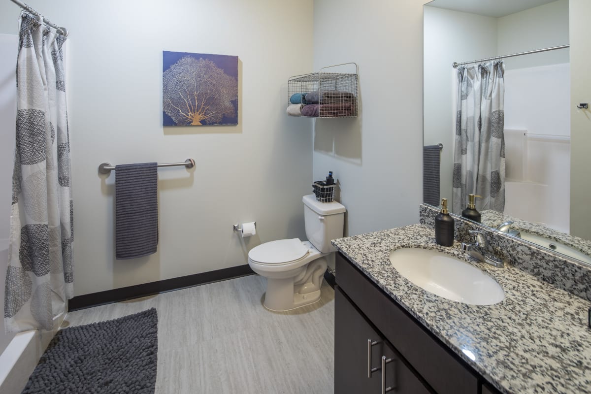 Large bathroom with a shower and vanity with granite countertops at The Foundry in Ames, Iowa