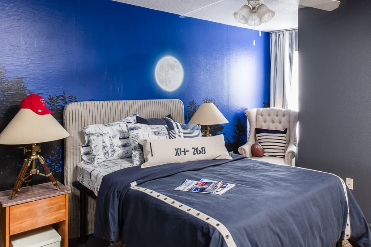 Model bedroom with a blue accent wall at The Holly in Lubbock, Texas