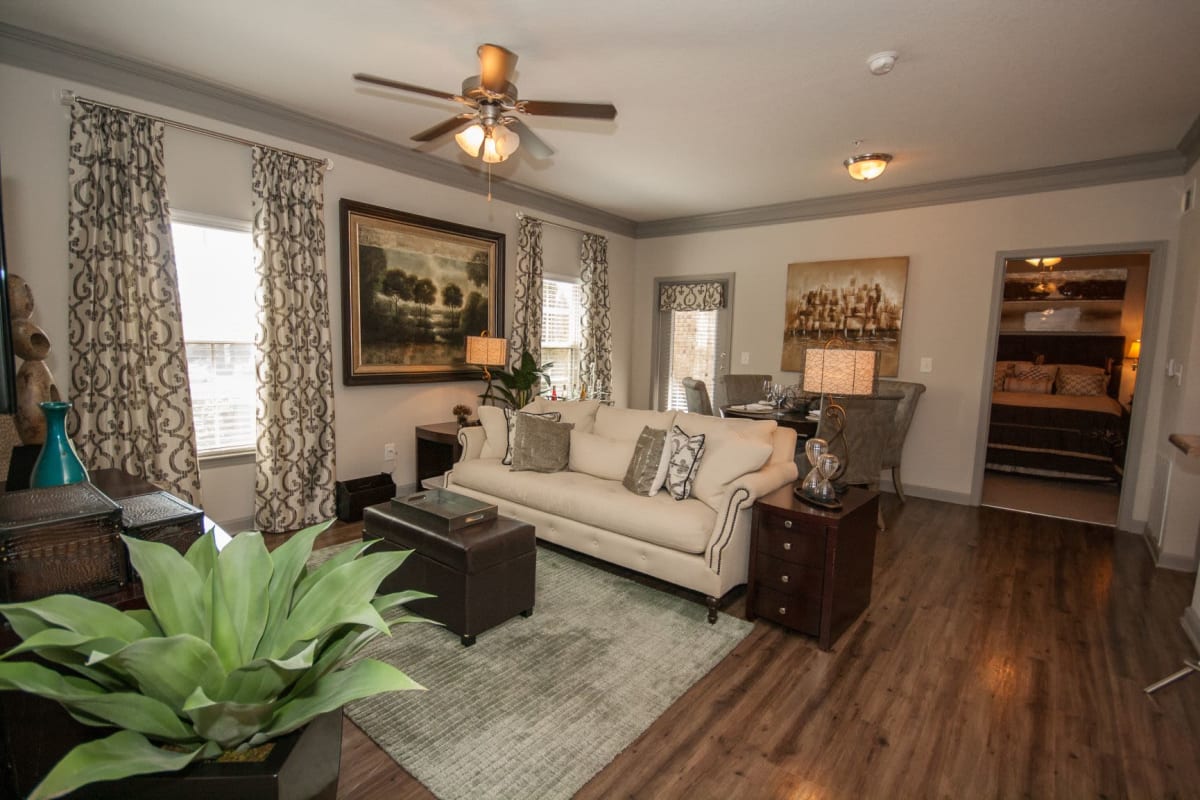 Beautifully decorated modern living room and dining area with wood-style flooring and a ceiling fan at Estates at McDonough Apartment Homes in McDonough, Georgia