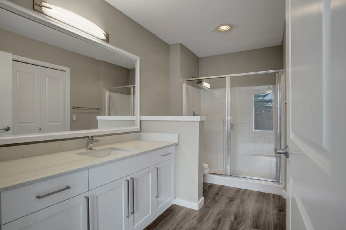 Large primary bathroom with a spacious quartz countertop and oversized vanity mirror at 700 Broadway in Seattle, Washington