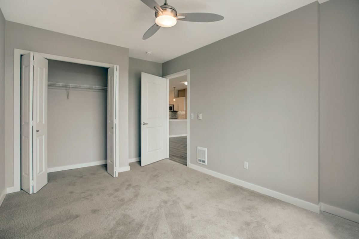 Plush carpeting, ample closet space, and a ceiling fan in a model apartment's bedroom at 700 Broadway in Seattle, Washington