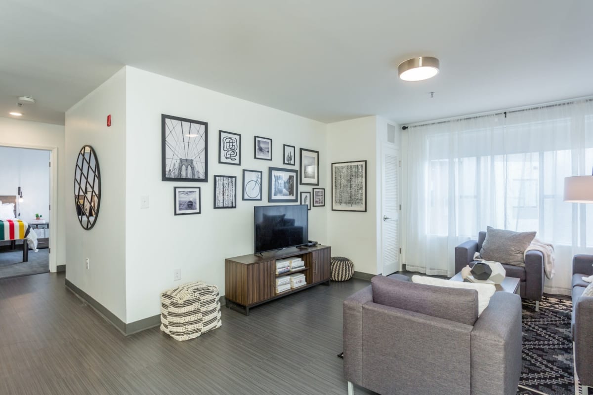 Spacious living room with wood-style flooring in a model student apartment at The Altitude in Harrisonburg, Virginia