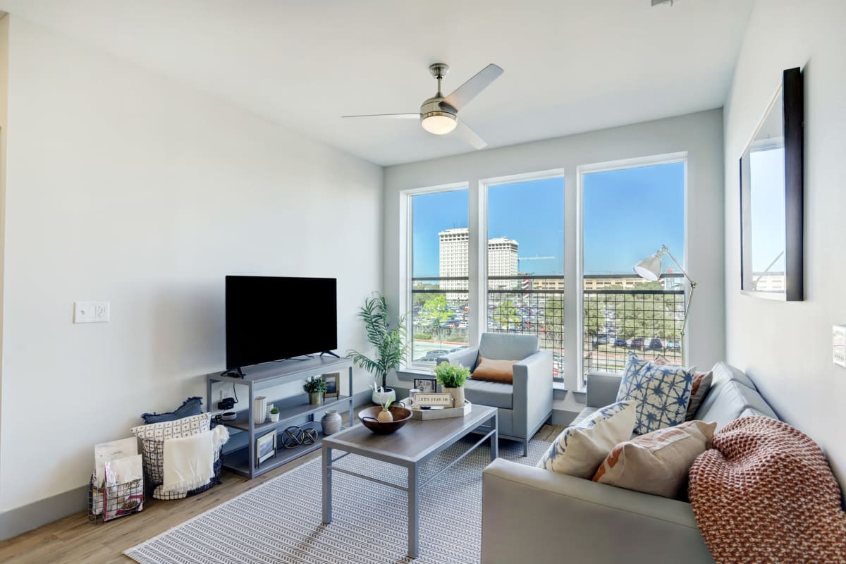Model living room with wood-style flooring and a ceiling fan at Tower 5040 in Houston, Texas