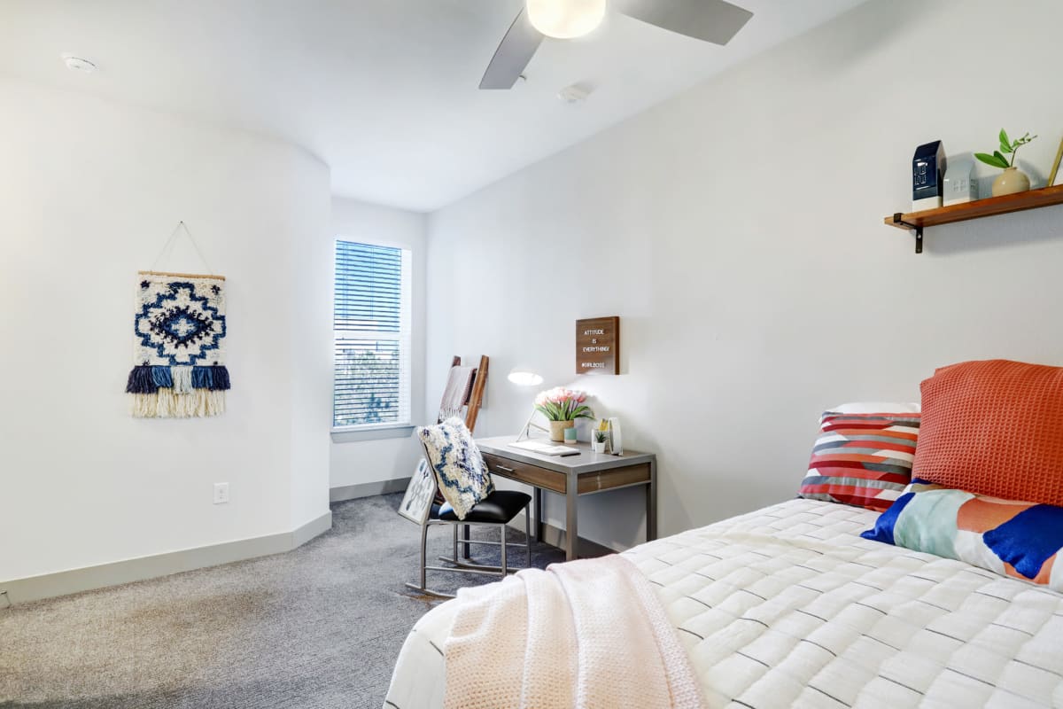 Spacious model bedroom with a desk and ceiling fan at Tower 5040 in Houston, Texas