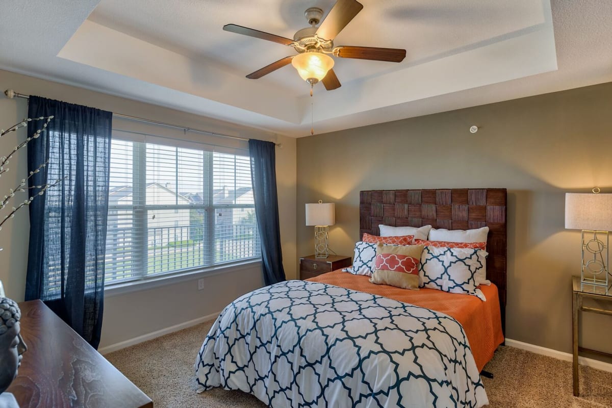 Model bedroom with large windows at The Residences at New Longview in Lees Summit, Missouri