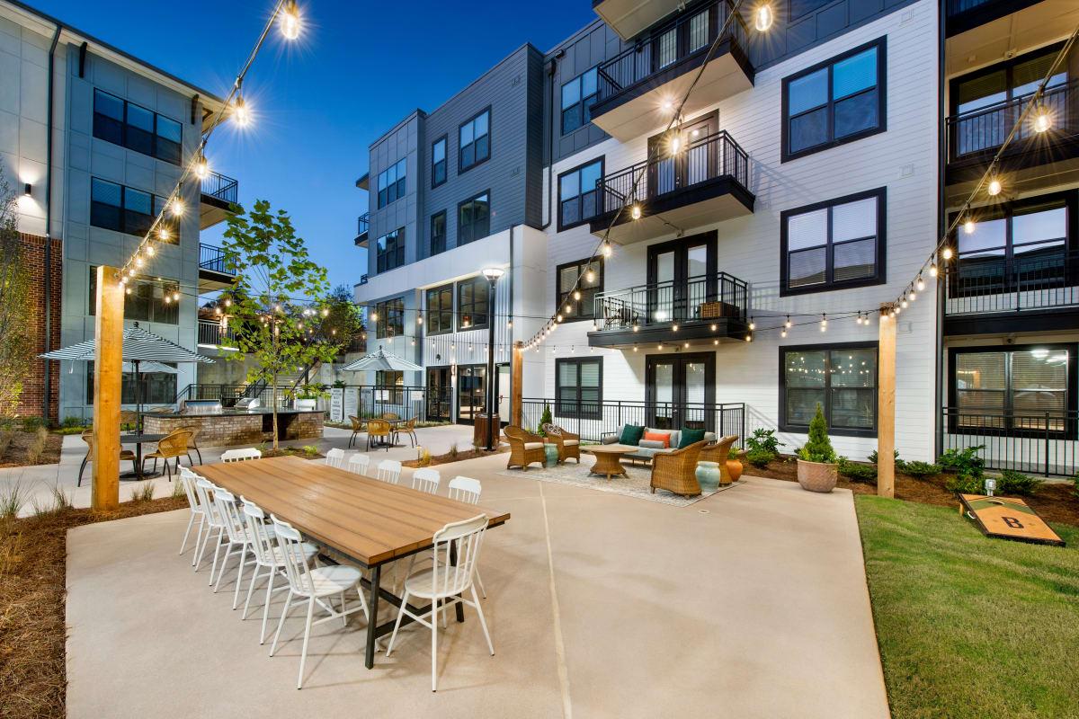 Outdoor gathering area with dining table and lawn games at The Brunswick in Norcross, Georgia