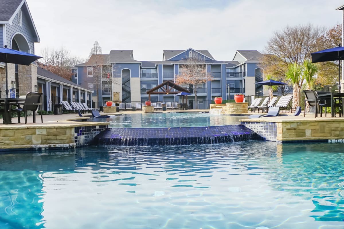 Glistening outdoor pool with a waterfall at The Leonard in Denton, Texas