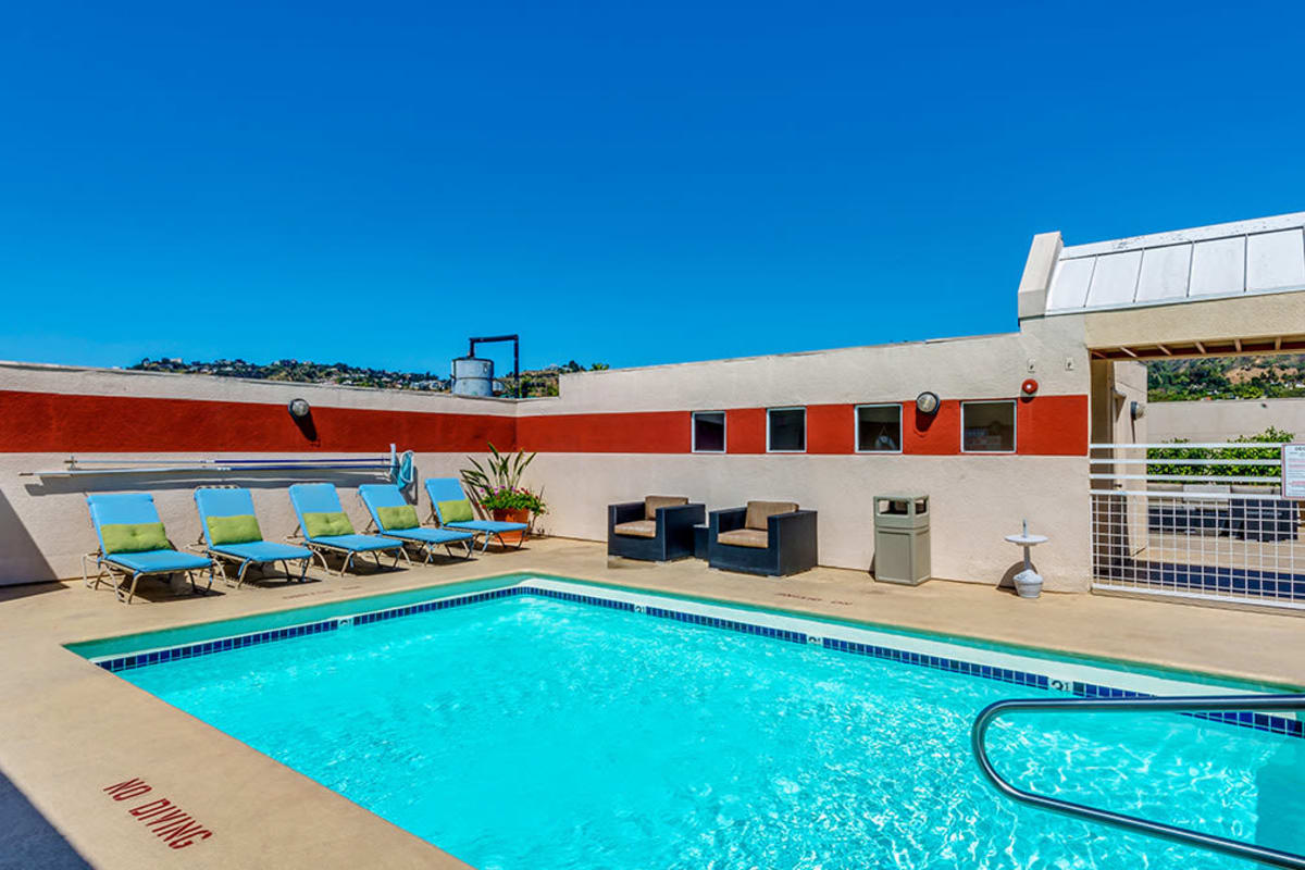 Resort-style pool surrounded by lounge chairs at The Joshua Apartments in Los Angeles, California