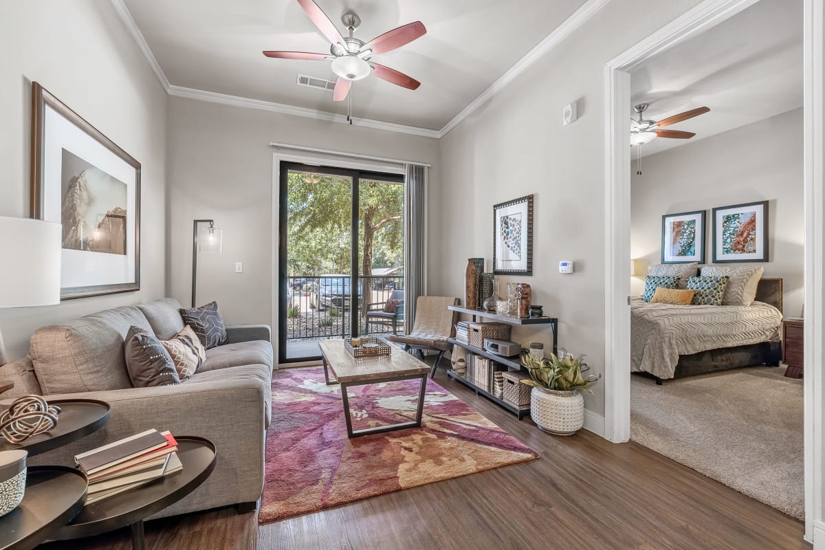 Bright and open living room with with wood floors and carpeted bedroom at Marquis at Barton Trails in Austin, Texas