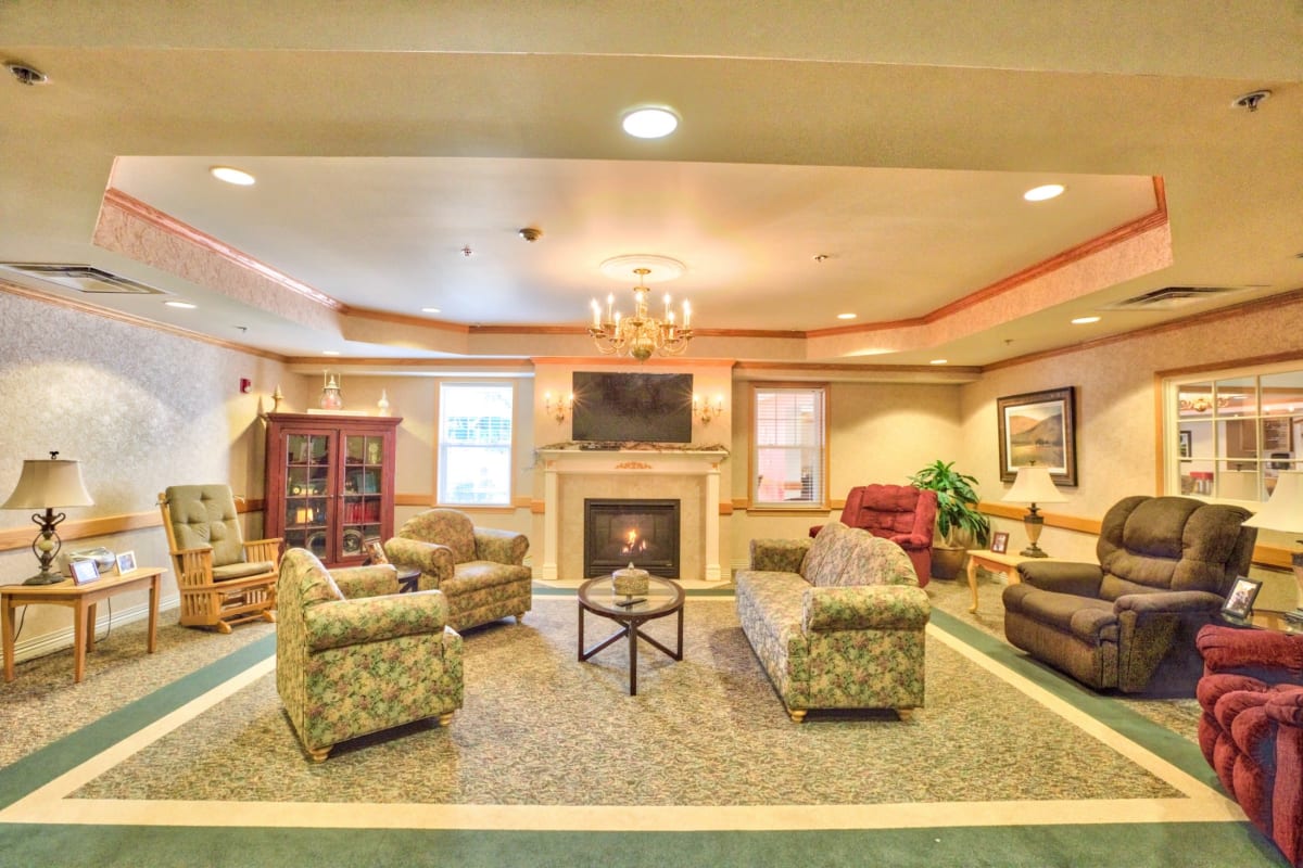 Lounge area with seating and stone fireplace at Trustwell Living at Westwood Place in Woodsfield, Ohio
