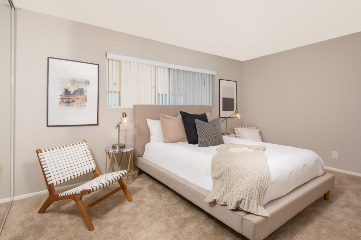 Furnished apartment bedroom with cozy blankets and throw pillows at Arbor Ridge Apartments in Whittier, California