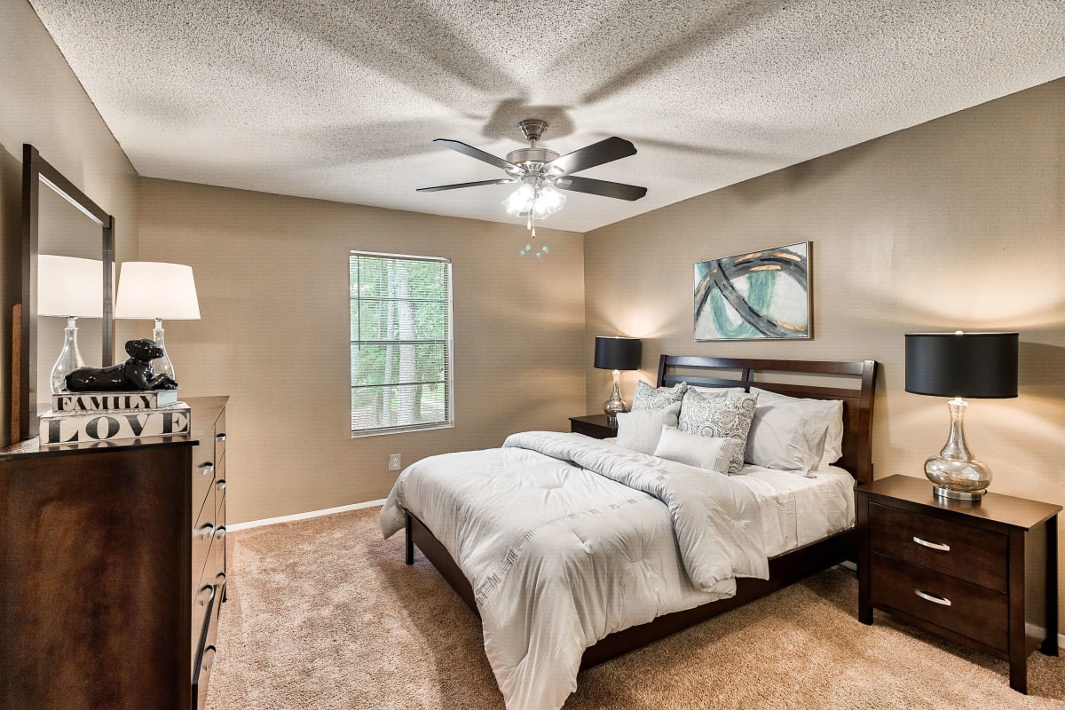 Resident master bedroom with a ceiling fan at Knollwood in Mobile, Alabama