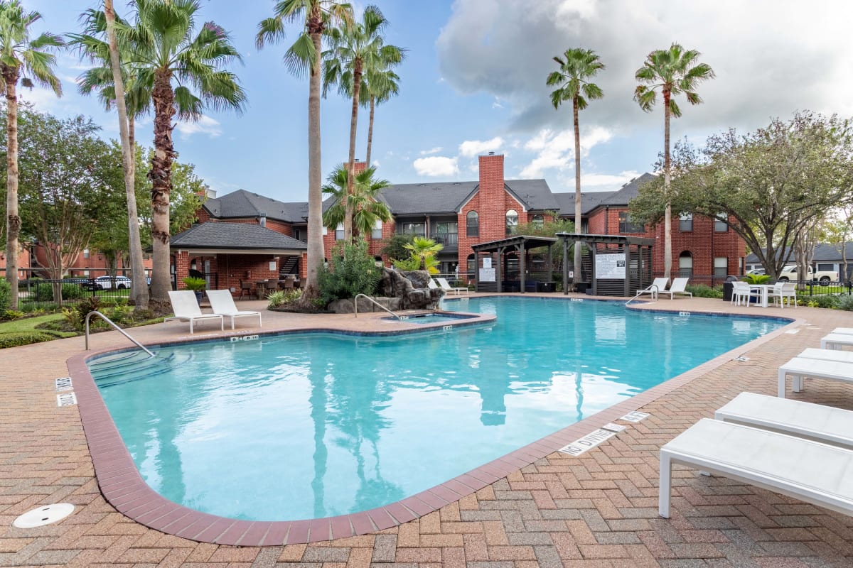 Palm tree lined outdoor community pool with lounge chairs at The Park at Waterford Harbor in Kemah, Texas