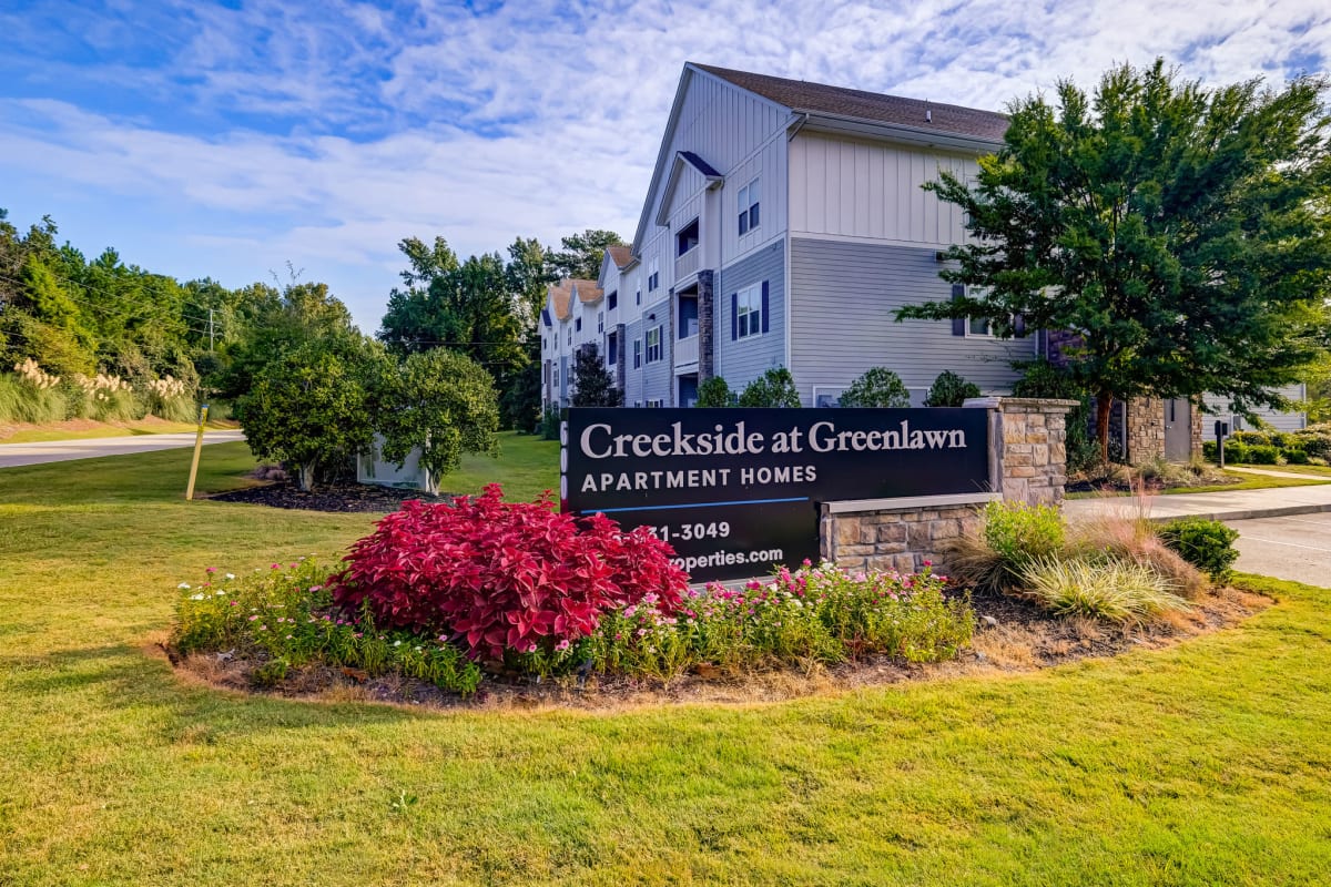 Entrance sign surrounded by flowers at Creekside at Greenlawn Apartment Homes in Columbia, South Carolina