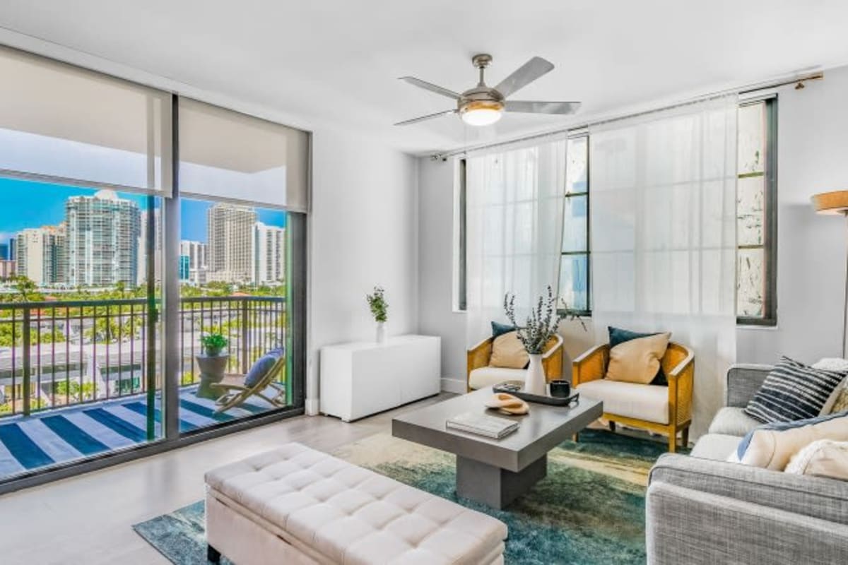 A furnished model apartment living room with a sliding door to the balcony at Marina Del Sol in Sunny Isles Beach, Florida