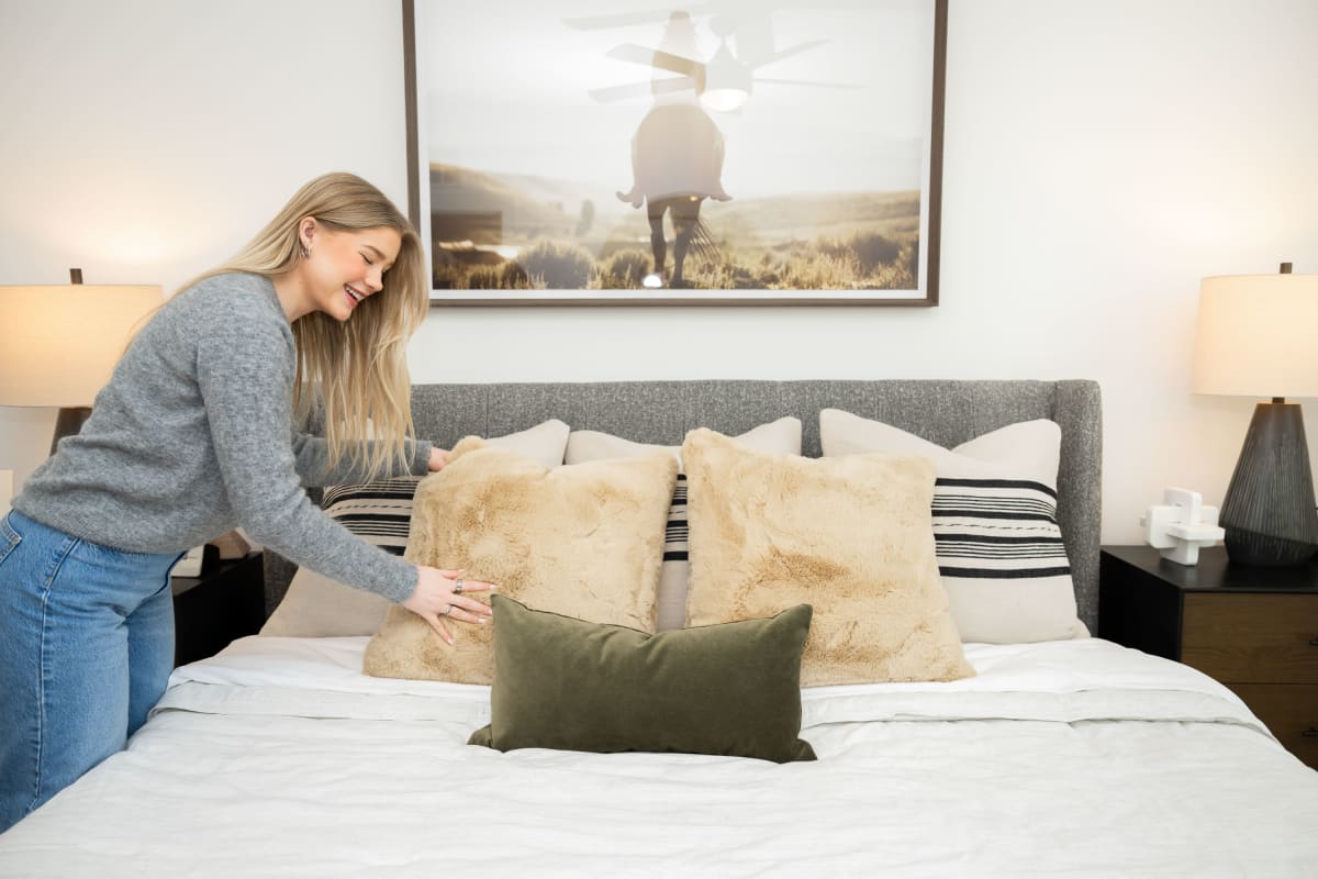 Resident making the bed in her stylish apartment home at The Scottie in Nashville, Tennessee