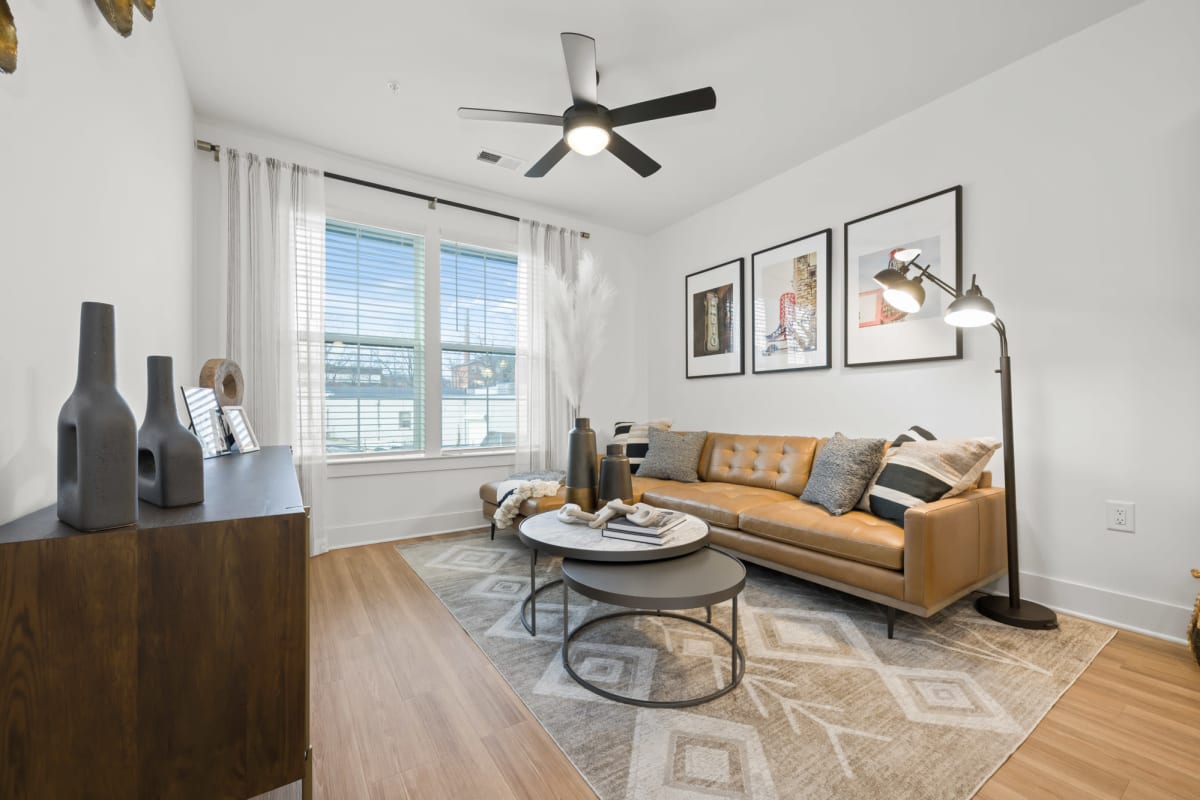 Model apartment living room with hardwood-style flooring and a ceiling fan at The Scottie in Nashville, Tennessee